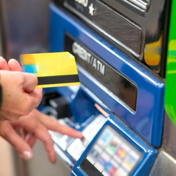 frau steht vor atm mit geldkarte
