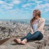 Au pair sitzt auf Mauer und schaut auf eine Stadt