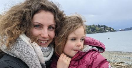 Au pair mit Gastkind auf dem Schoß am Strand