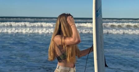 Au pair mit Surfbrett am Strand