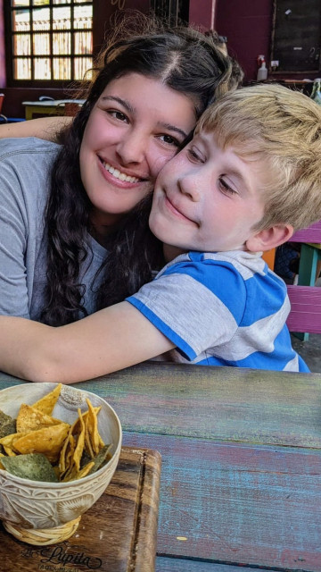 Au pair umarmt Gastkind im Restaurant