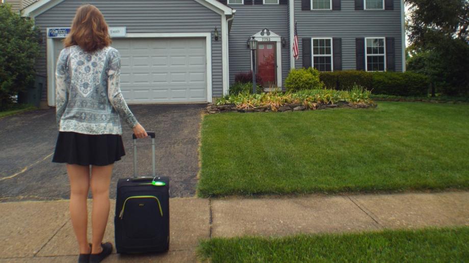 au pair steht mit koffer vor haus in den usa