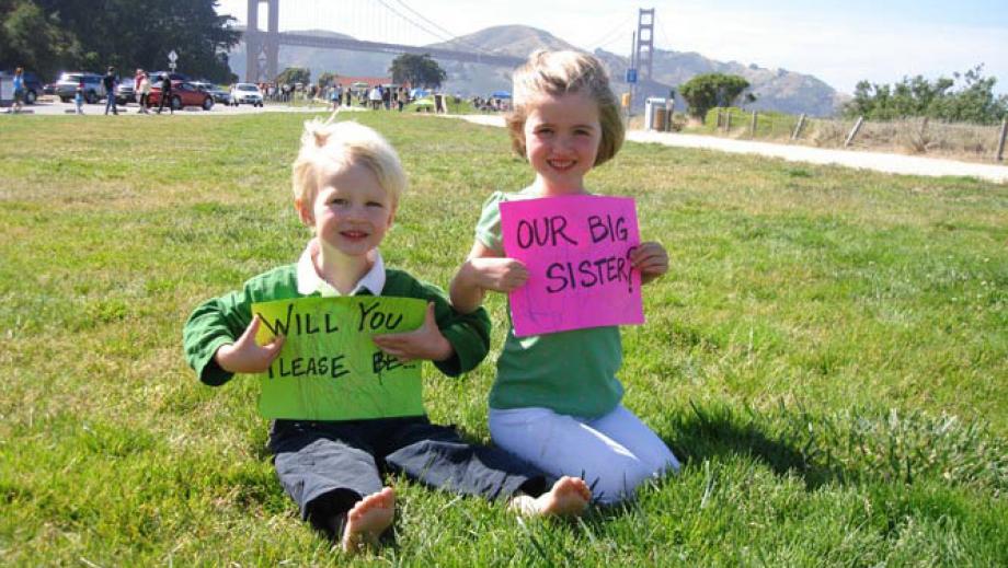 gastkinder halten schilder hoch "will you be our big sister?"