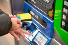 frau steht vor atm mit geldkarte