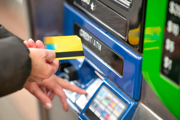 frau steht vor atm mit geldkarte
