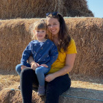 Au-pair mit Gastkind auf Heuballen sitzend