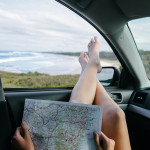 Beine einer Person im Auto, die sich eine Landkarte anschaut